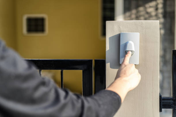 man's hand pressing a doorbell button with sunlight. close up hand and finger visiter ringing buzzer doorbell. guest press bell behind front door home. - ringing bell imagens e fotografias de stock