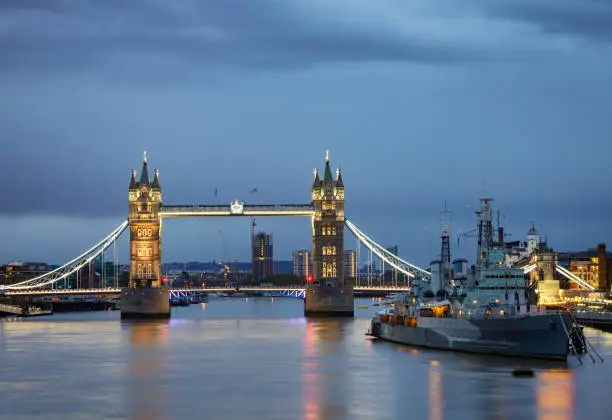 Photo of London cityscape with illuminated Tower Bridge and HMS Belfast