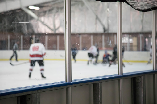 Boards at a hockey rink with a game going on behind