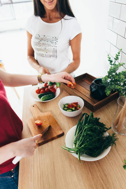 istock Two girls friends preparing dinner in kitchen cooking salad. 924440816