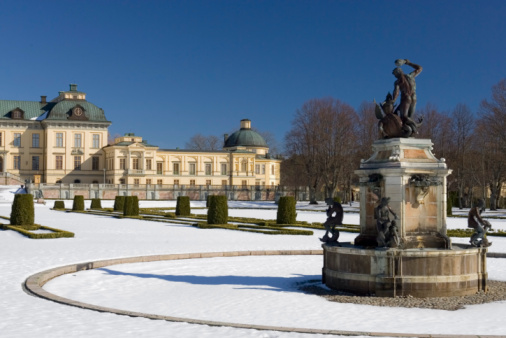 View of Drottningholm palace in winter, with the Hercules fountain in the foreground.