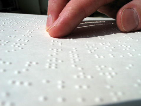 Fingers going across a page of Braille text.