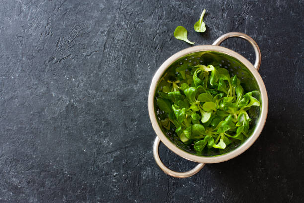istock Lettuce corn in the colander over black stone background 924449930
