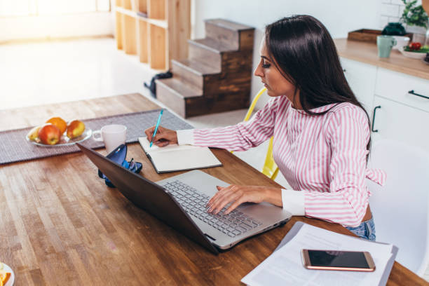 istock Concentrated freelancer woman making notes from internet working home sitting at table 924450618