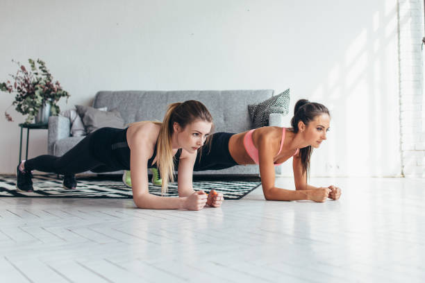 dos mujeres fit tabla ejercicio en piso en casa entrenamiento detrás y presionar los músculos, el deporte, el entrenamiento de fitness - board sports fotografías e imágenes de stock