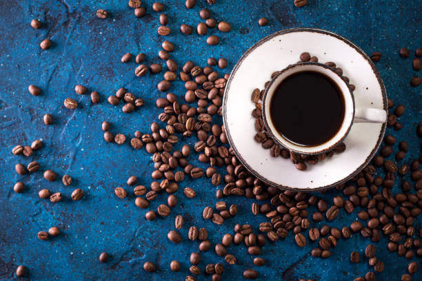 istock Coffee cup and coffee beans on a dark blue table 924460424