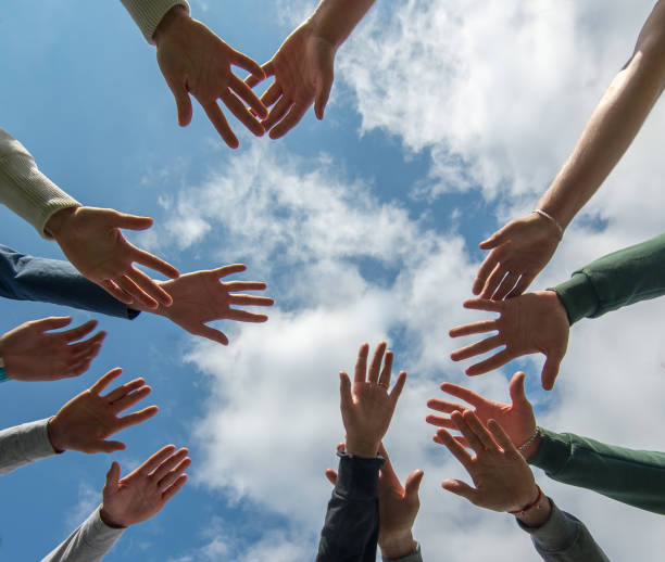 istock Hands stretch towards each other against a blue sky with white clouds 924460518