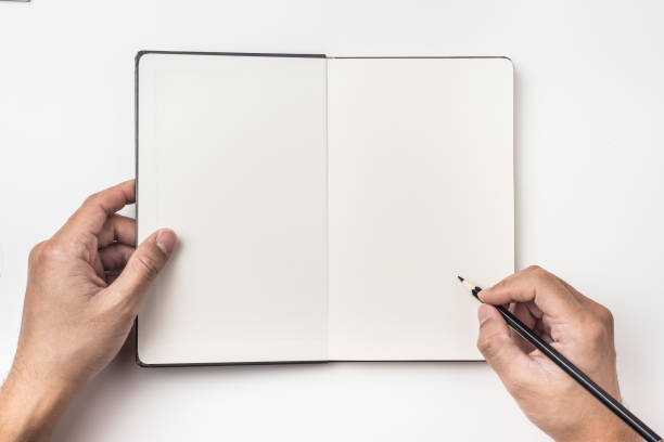 istock man's hand hold black pencil above black hardcover notebook 924464210