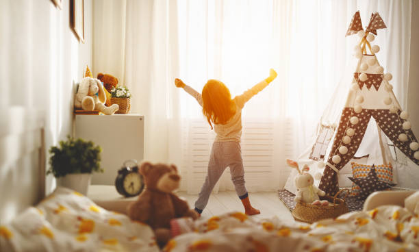 bambina si sveglia e si allunga al mattino a letto e si allunga - bed child smiling people foto e immagini stock