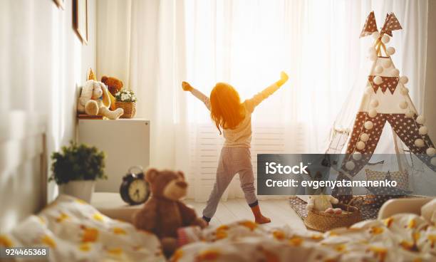 Child Girl Wakes Up And Stretches In Morning In Bed And Stretches Stock Photo - Download Image Now