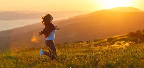 Happy woman   on the sunset in nature in summer with open hands
