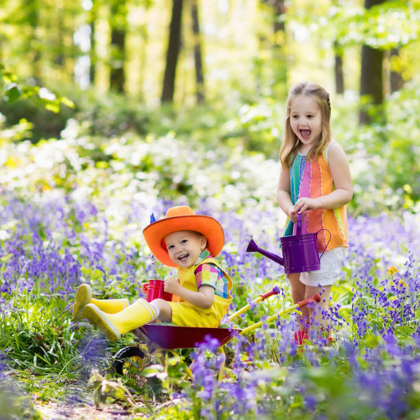 istock Kids with bluebell flowers, garden tools 924469274