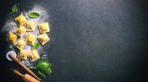 ravioli mit spinat und ricotta auf dunklem hintergrund - pasta raw traditional culture heap stock-fotos und bilder