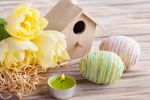 Green easter eggs, yelow tulips on wooden background