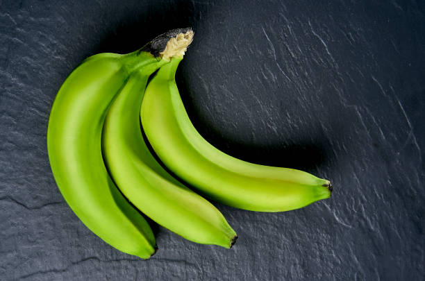 istock green bananas on a black background 924486736