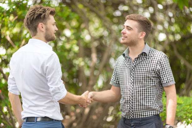 istock young business friends standing at park and shaking hands. 924491584