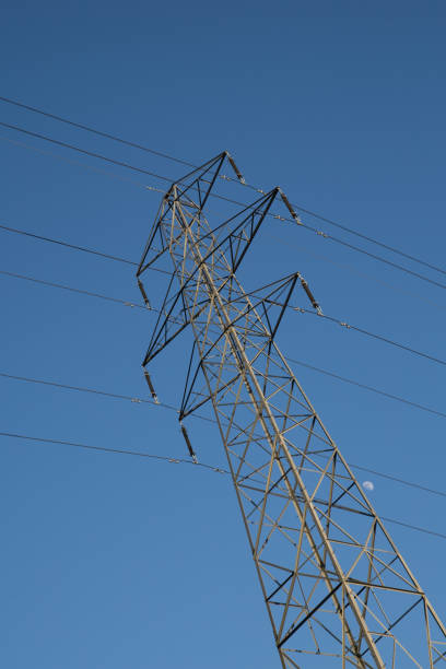 istock electricity pylon against blue sky with moon 924491780
