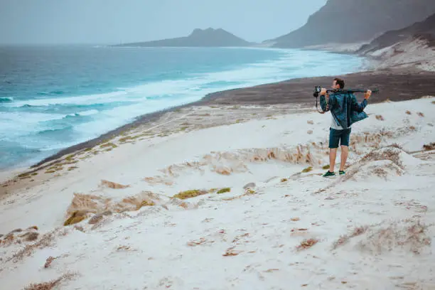 Photo of Photographer admitting unique others worldly landscape of sand dunes volcanic cliffs on the Atlantic coast. Baia Das Gatas, near Calhau, Sao Vicente Island Cape Verde