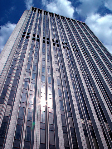 Towering office building in front of nice blue sky and puffy clouds