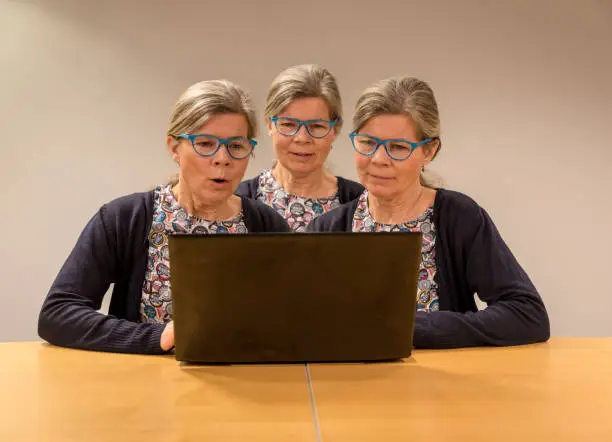 Oslo, Norway - February 17, 2018: Three clones og one elderly women working with a pc showing different facial expressions.