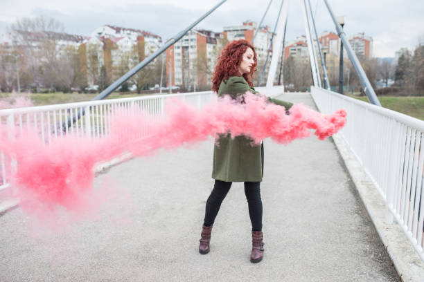 istock Hipster redhead girl having fun with colored smoke 924505490