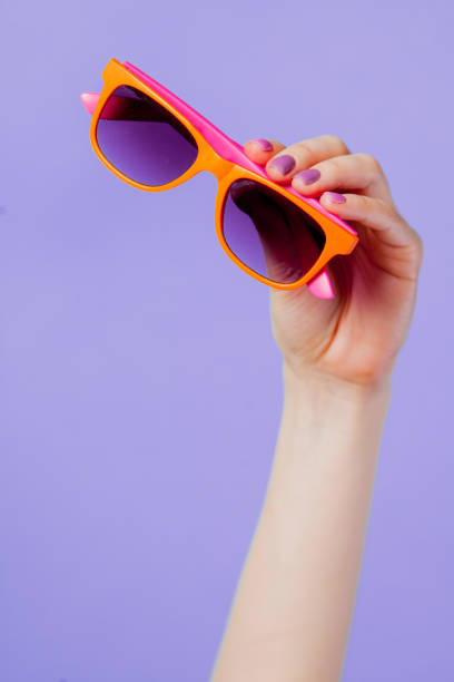 istock Female hand holding orange eyeglasses 924512422