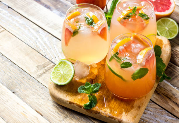 Grapefruit and mint gin cocktail, refreshing drink Grapefruit and mint gin cocktail, refreshing drink with ice on wooden background. Selective focus punch drink stock pictures, royalty-free photos & images