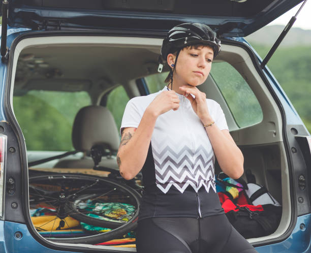 weibliche radfahrer setzt auf ihre fahrradausrüstung und reißverschlüsse ihr trikot - cyclist cycling road women stock-fotos und bilder