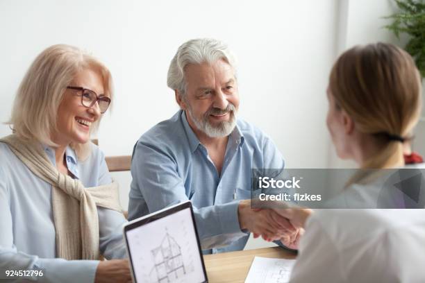 Happy Older Family And Real Estate Agent Shake Hands Buying New House Stock Photo - Download Image Now