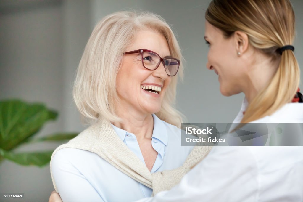Beautiful glücklich im Alter von Frau umarmen junge Erwachsene Tochter und lachen - Lizenzfrei Freundschaft Stock-Foto