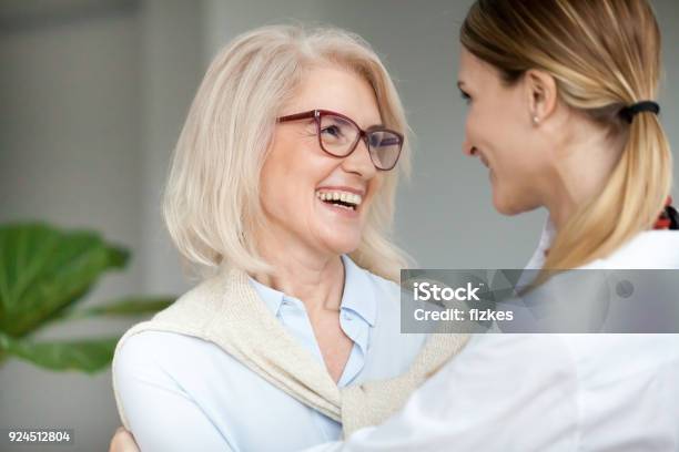 Beautiful Happy Aged Woman Embracing Young Adult Daughter And Laughing Stock Photo - Download Image Now