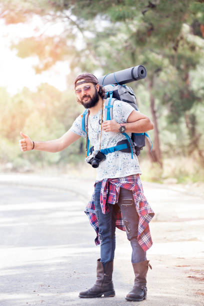 istock Man with hat and backpack hitchhiking on the road 924516654