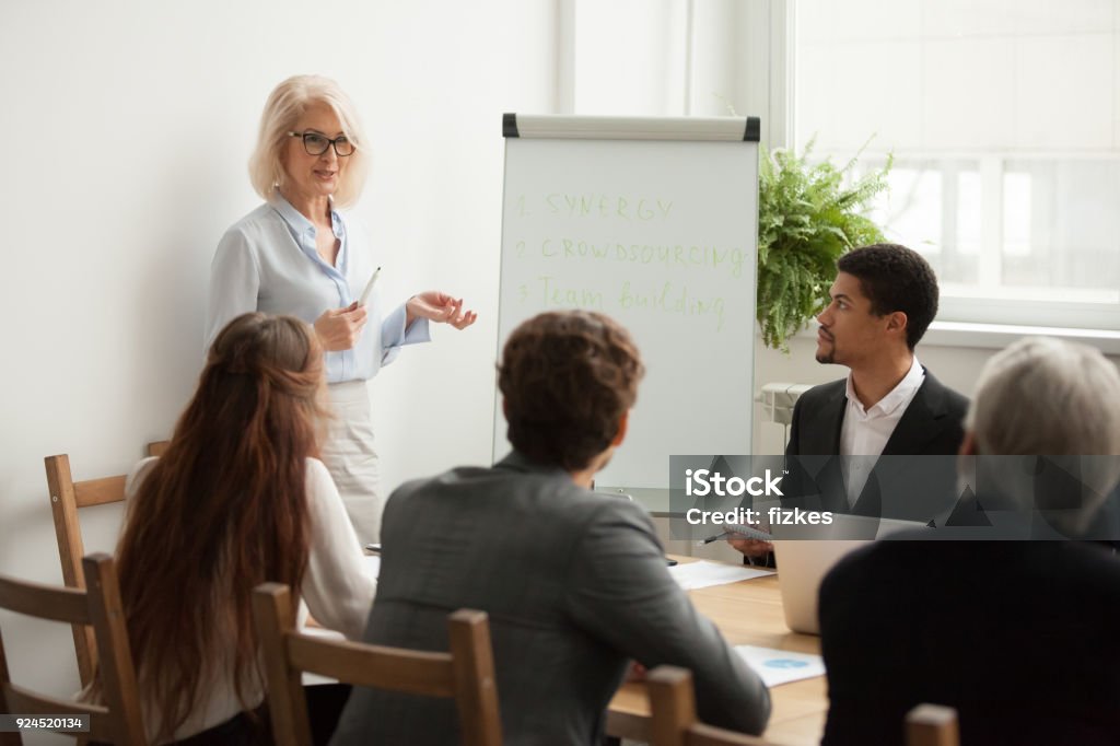 Envelhecido empresária atraente fará apresentação na reunião de equipe corporativa - Foto de stock de Ensinar royalty-free