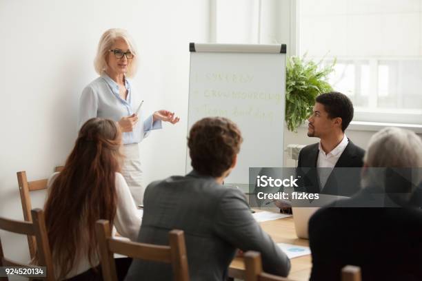 Foto de Envelhecido Empresária Atraente Fará Apresentação Na Reunião De Equipe Corporativa e mais fotos de stock de Ensinar