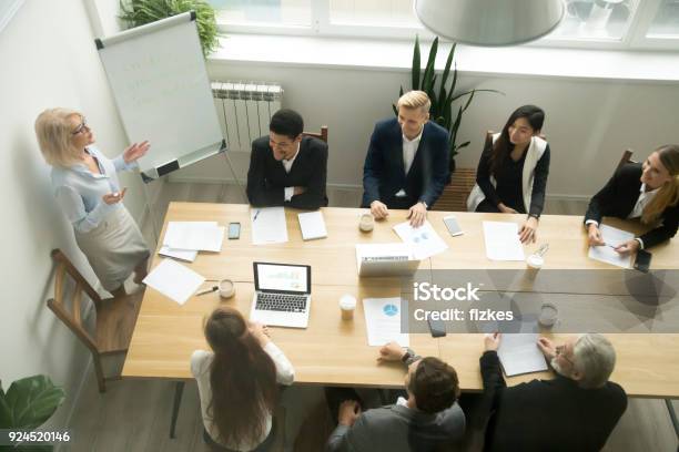 Aged Senior Businesswoman Giving Presentation At Multiracial Group Office Meeting Stock Photo - Download Image Now