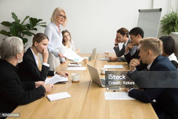 Senior Woman Boss Scolding Employees For Bad Work At Meeting Stock Photo - Download Image Now