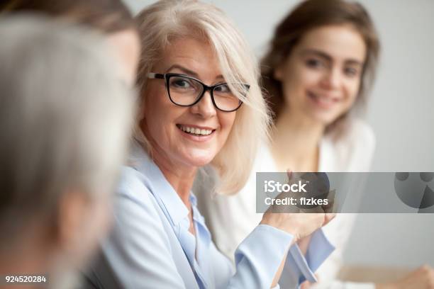 Sonriendo De Años Empresaria Buscando Escuchar A Colega En Reunión De Equipo Foto de stock y más banco de imágenes de Tercera edad