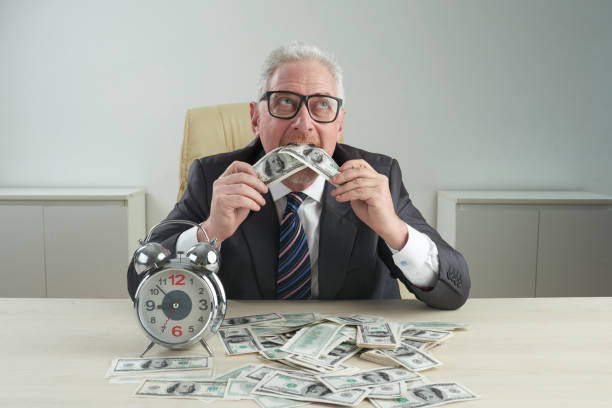 Eating money Pensive aged businessman eating money on his table vietnamese old man portrait stock pictures, royalty-free photos & images