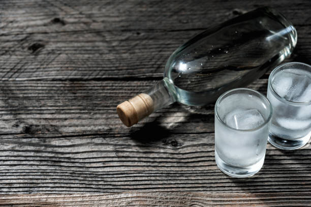 istock Two shot glasses with cold vodka or gin on wooden table, 924520646