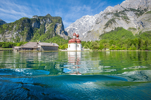 Classic panoramic view of Lake Konigssee with world famous Sankt Bartholomae pilgrimage church and Watzmann mountain on a beautiful sunny day in summer, Berchtesgadener Land, Bavaria, Germany