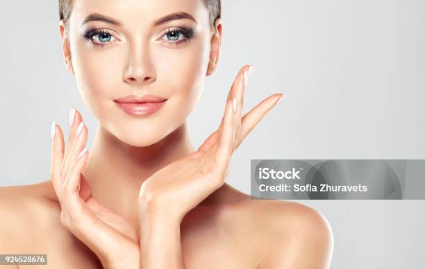 Gorgeous Young Woman With Clean Fresh Skin Is Touching Own Face Light Smile On The Perfect Face Cosmetology Stock Photo - Download Image Now