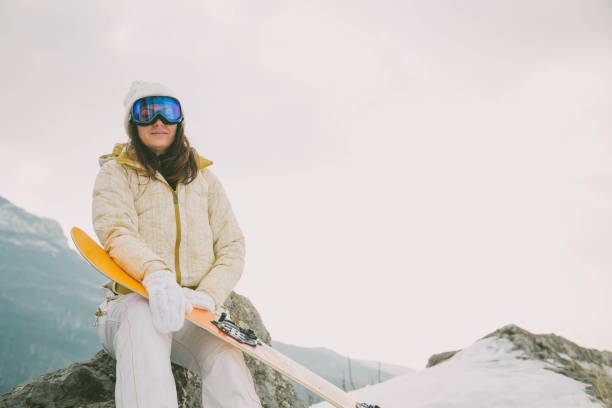 istock Woman holding snowboard with mountains in background 924531368