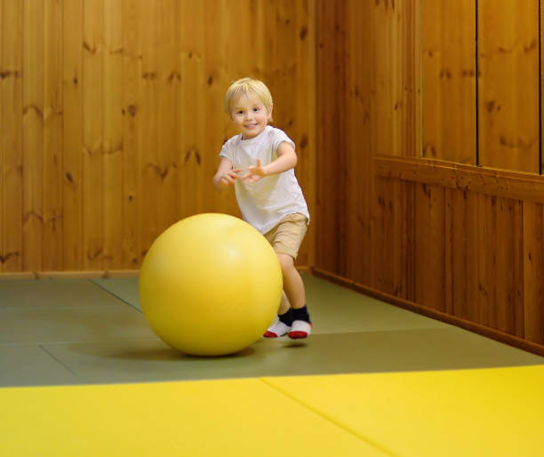 active preschool boy playing with big ball in indoor sports hall/gym class - small gymnastics athlete action imagens e fotografias de stock