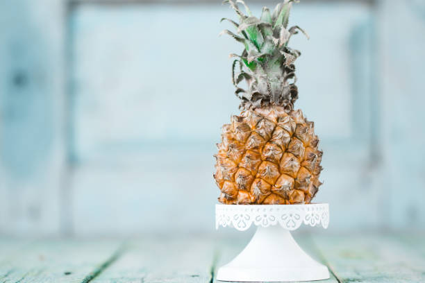 Ripe baby pineapple on a wooden background, tropical fruits