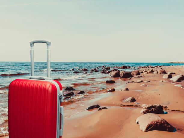 istock Red suitcase on the sandy shore of the bay. 924537212