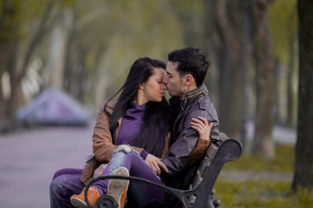Shot of a loving couple sitting on a bench overlooking the ocean