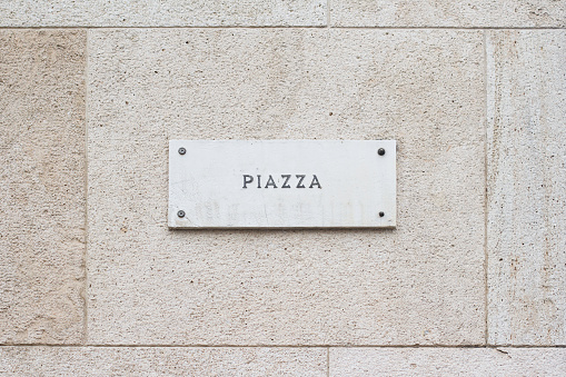 horizontal closeup of square empty marble plaque signboard with the word piazza written on a building with classic architecture