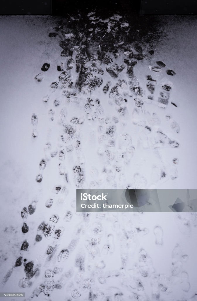 Footprints in the snow Many footprints in the snow leading towards a door, seen directly from above. Aerial View Stock Photo