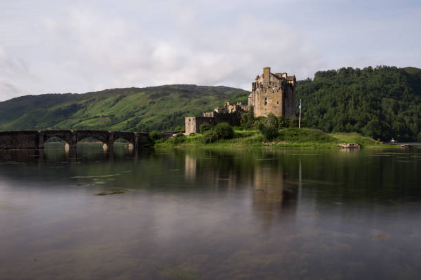 Dornie, Scotland, UK - July 5, 2016: Famous Eilean Donan Castle in Scotland, UK. A cloudy morning with high loch waters surrounding the island the castle sits upon.