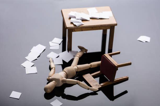 Unconscious Wooden Dummy Figure Lying On Floor With Scattered Documents At Workplace